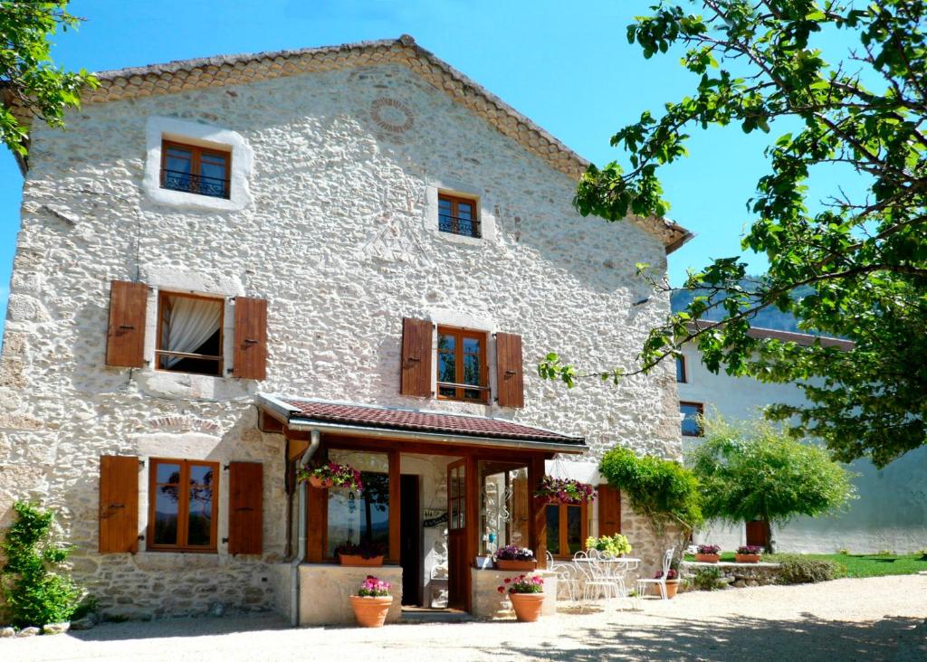 Saint-Martin-en-VercorsLa ferme du Château的一座大型白色石头建筑,设有木窗