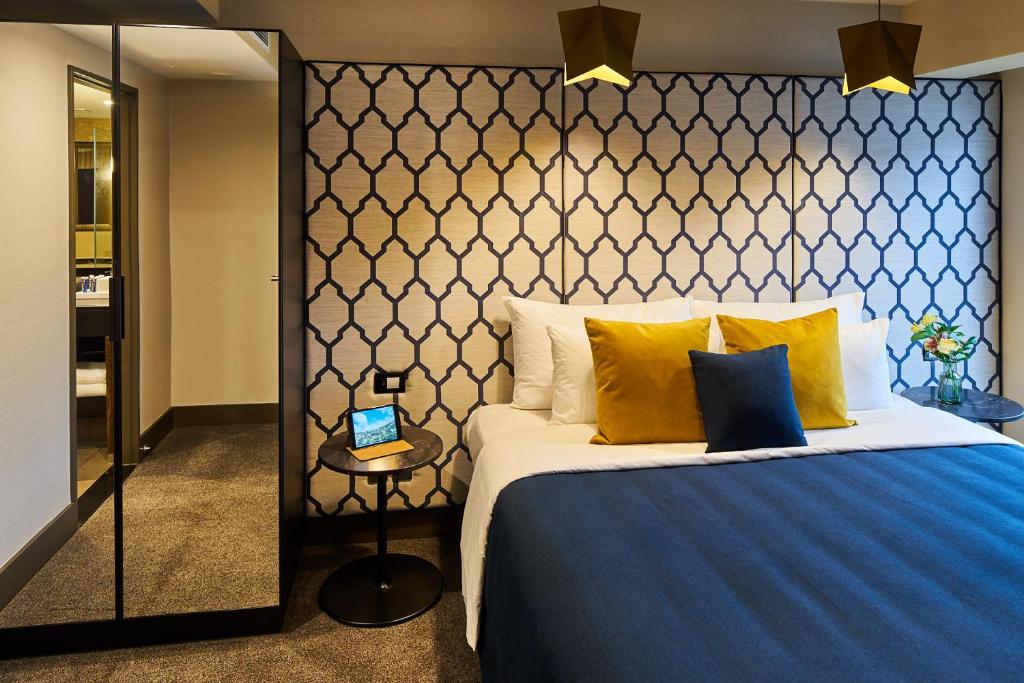 惠灵顿博尔顿酒店的一间卧室配有一张大床,提供蓝色毯子和黄色枕头