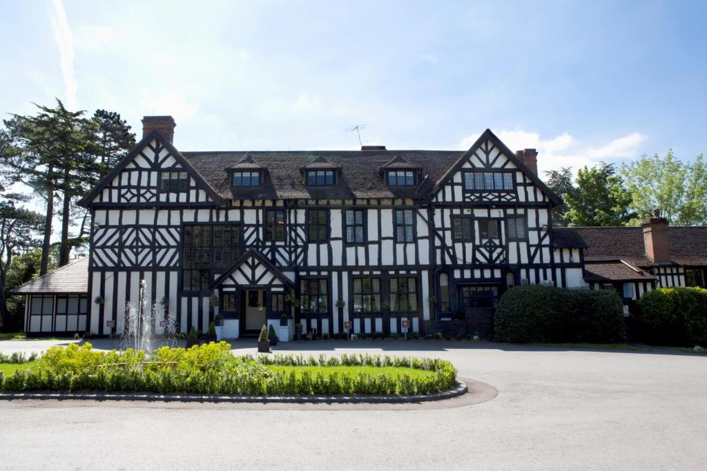 埃尔斯特里The Manor Elstree的一座黑白的古老建筑,设有喷泉