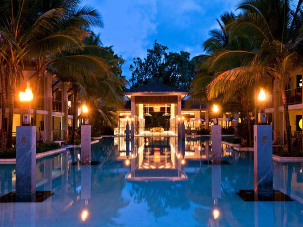 道格拉斯港Luxury Apartments at Temple Resort and Spa Port Douglas的夜间带游泳池的度假村