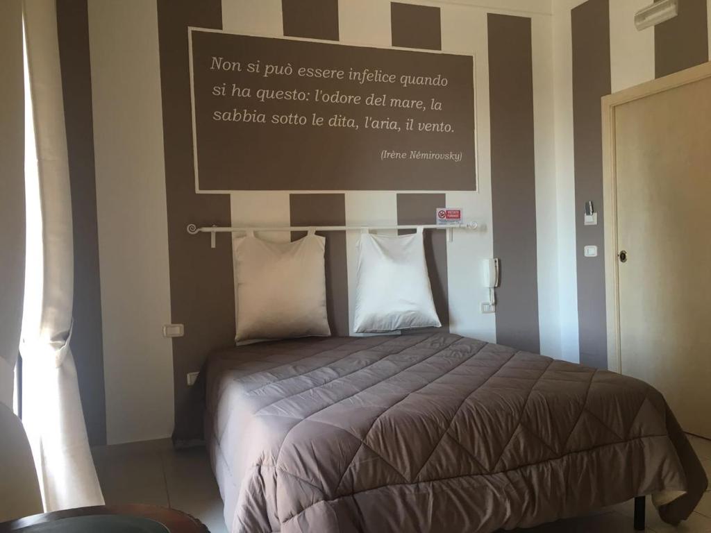 玛格丽塔萨沃亚La Perla delle Saline的卧室配有一张挂有墙上标志的床