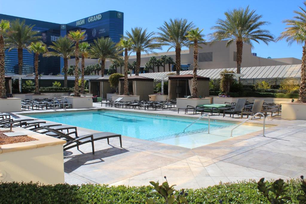 拉斯维加斯签名豪华套房国际酒店的一个带躺椅和棕榈树的游泳池
