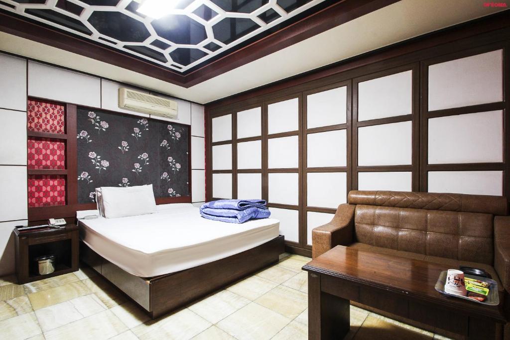 釜山普拉斯汽车旅馆的一间卧室配有一张床、一张桌子和一张沙发