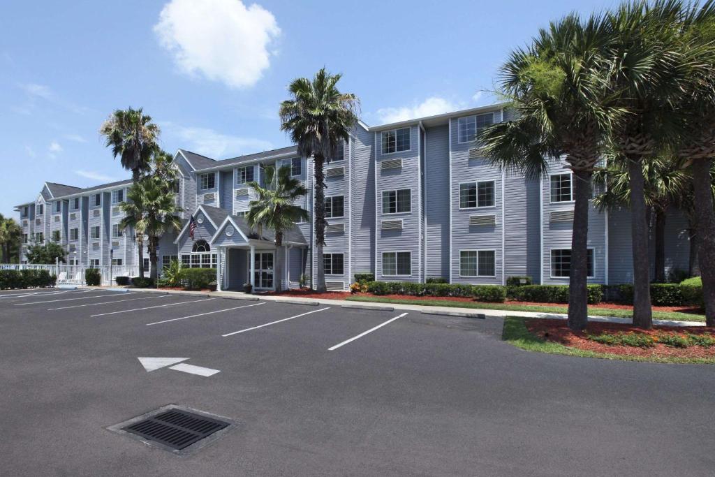 棕榈海岸Microtel Inn & Suites by Wyndham Palm Coast I-95的停车场内棕榈树的大型建筑