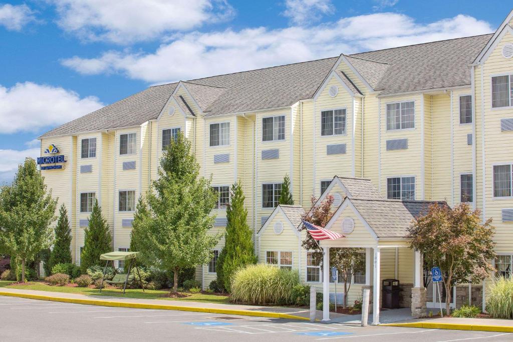 贝克利Microtel Inn & Suites Beckley East的前面有美国国旗的大型白色建筑