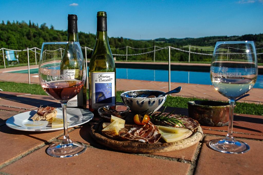 瓦尔的圣卡西亚诺吉内斯特拉生态农家乐的一张桌子,上面放着两杯葡萄酒和一盘食物