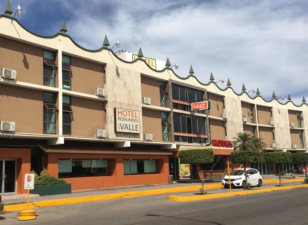 库利亚坎Hotel del Valle的一座酒店大楼,前面有停车位