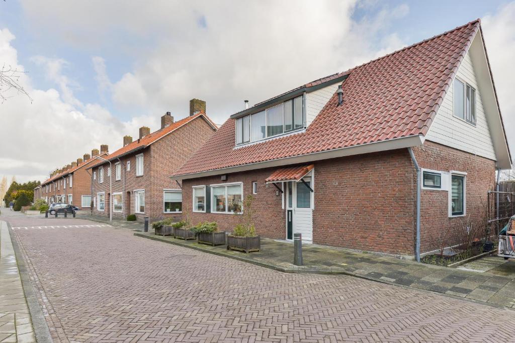哈尔夫韦赫Spacious Family Home Halfweg的街道上一座砖砌建筑,有红色屋顶
