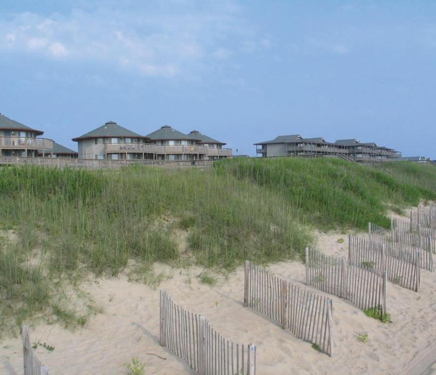 斩魔山Outer Banks Beach Club II Resorts的沙滩上一排围栏,有房子
