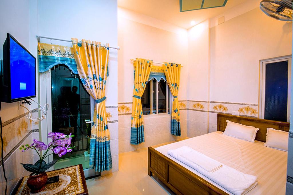 惹岛Motel Thuyền & Biển的一间卧室配有一张黄色窗帘的床和一台电视