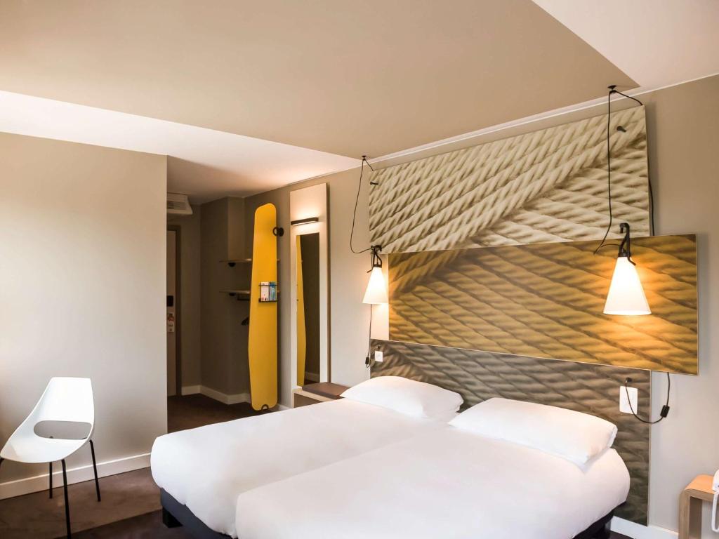 瓦夫尔瓦夫尔布鲁塞尔东宜必思酒店的一间卧室设有两张白色的床和黄色的墙壁