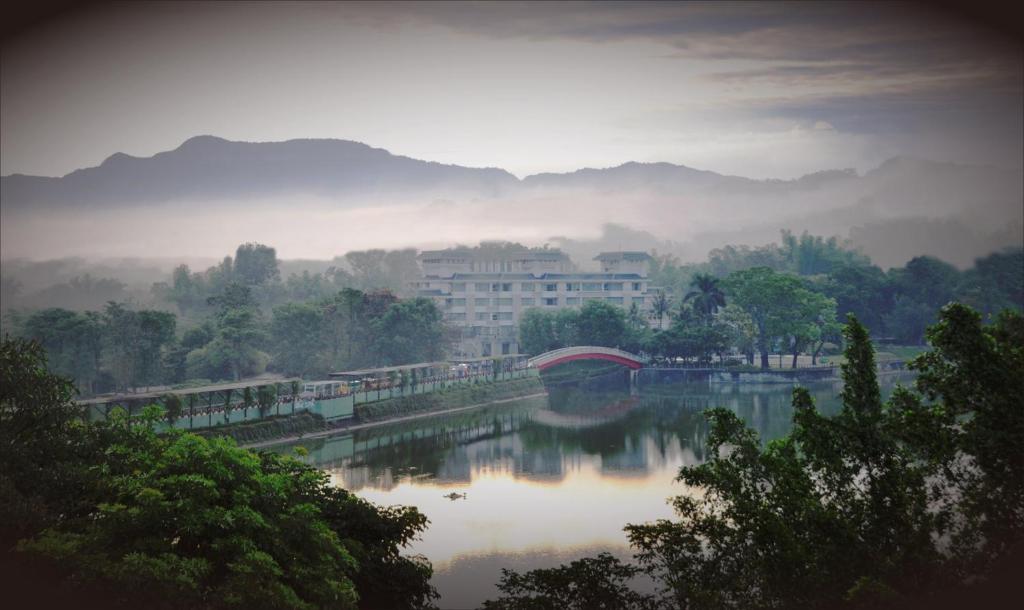 柳营柳營尖山埤 Liuying Jianshanpi Resort的一座河上的桥梁,有一座建筑的背景
