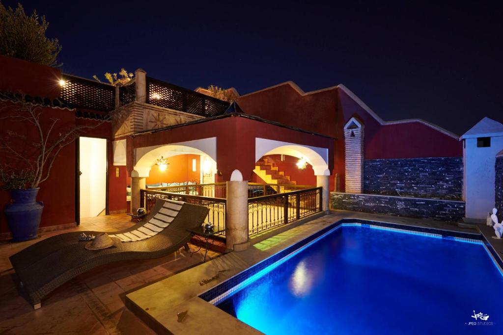 马拉喀什Riad Jenaï L'Authentique的夜间在房子前面的游泳池