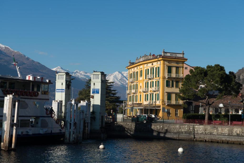 瓦伦纳奥利维多酒店的一座黄色的建筑,毗邻一条有山脉的河流