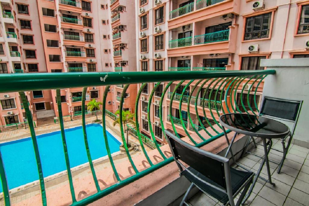 哥打京那巴鲁滨海码头公寓酒店的一个带桌椅的阳台和一个游泳池
