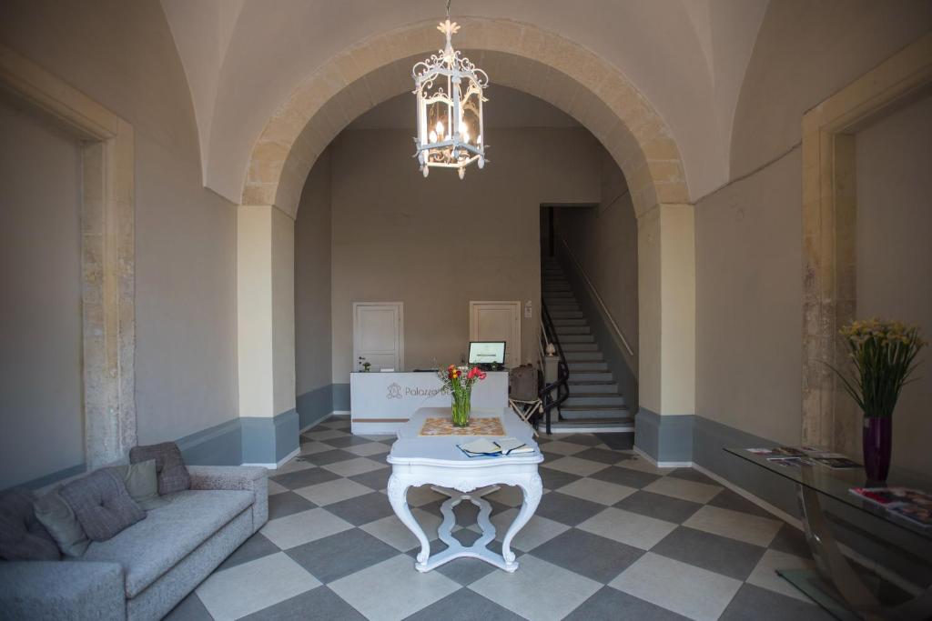 莱切Palazzo Belsanti的客厅配有桌子和吊灯