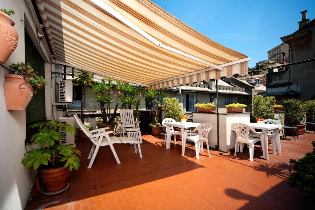 热那亚凯罗利酒店的庭院配有白色的桌椅和遮阳篷。