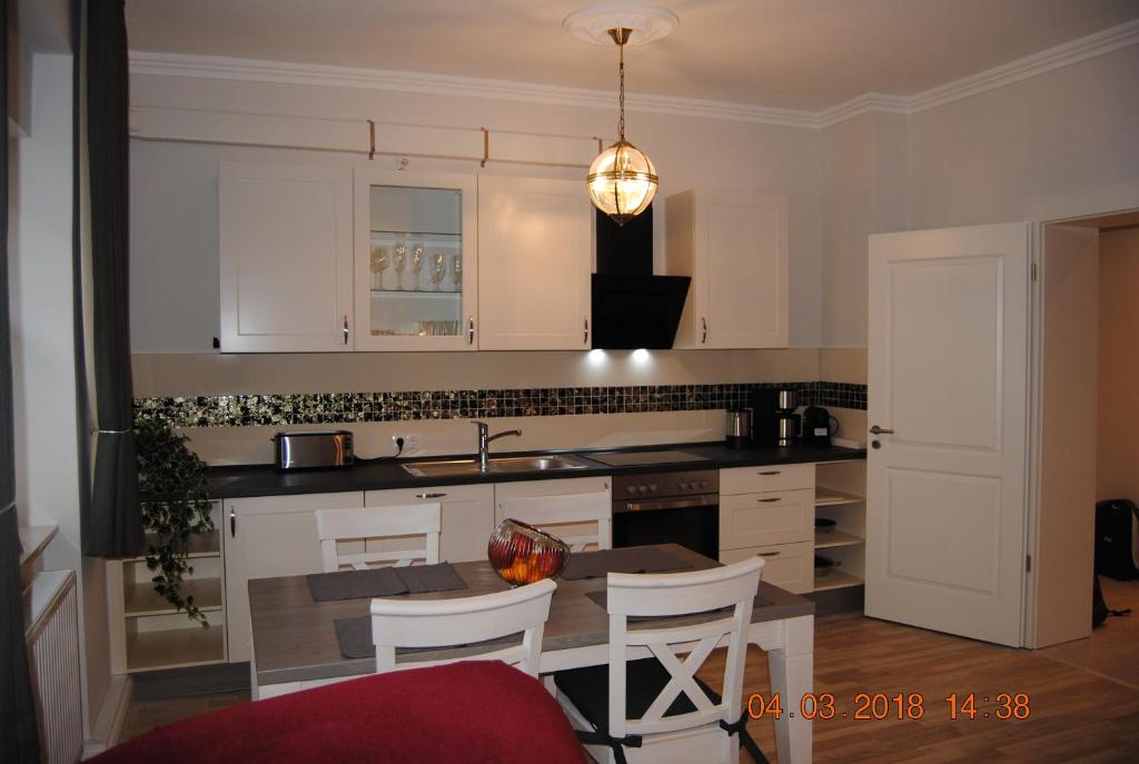 基尔Schöne Ferienwohnung zentral gelegen的厨房配有白色橱柜和桌椅