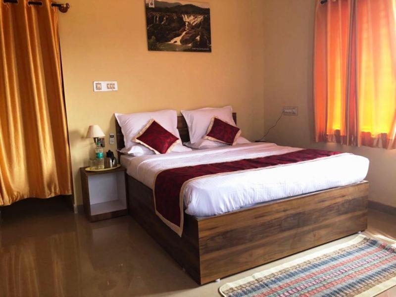 SivasamudramKSTDC Hotel Mayura Bharachukki, Shivanasamudra的卧室配有一张带白色床单和枕头的大床。