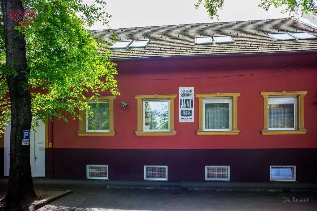 德布勒森Cívis Szálláshely的红色的建筑,有黄色的窗户和树
