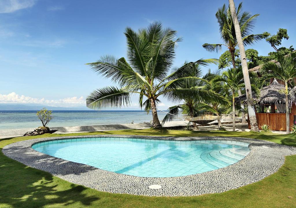 Ronda依塔克小屋度假村的毗邻大海的棕榈树游泳池
