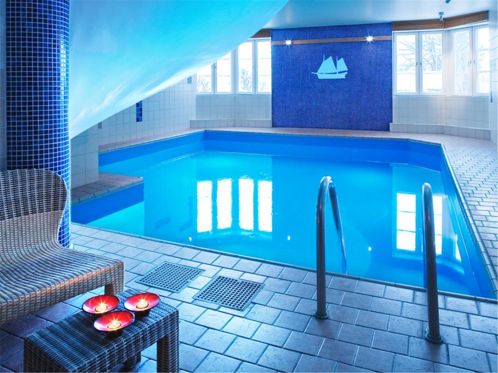 胡迪克斯瓦尔斯塔特优质酒店的一个带桌子和椅子的蓝色游泳池