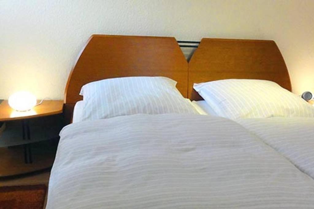 巴特德里堡Haus Harmonie的卧室配有一张白色大床和木制床头板