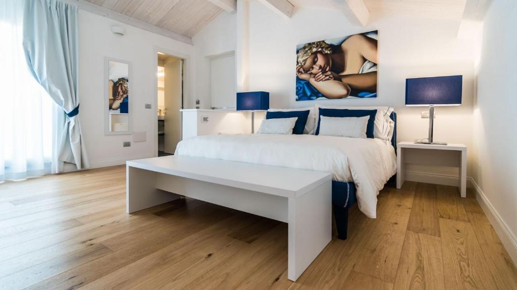 萨萨里Cafe Bleu Relais的白色的卧室配有白色的床和一张桌子