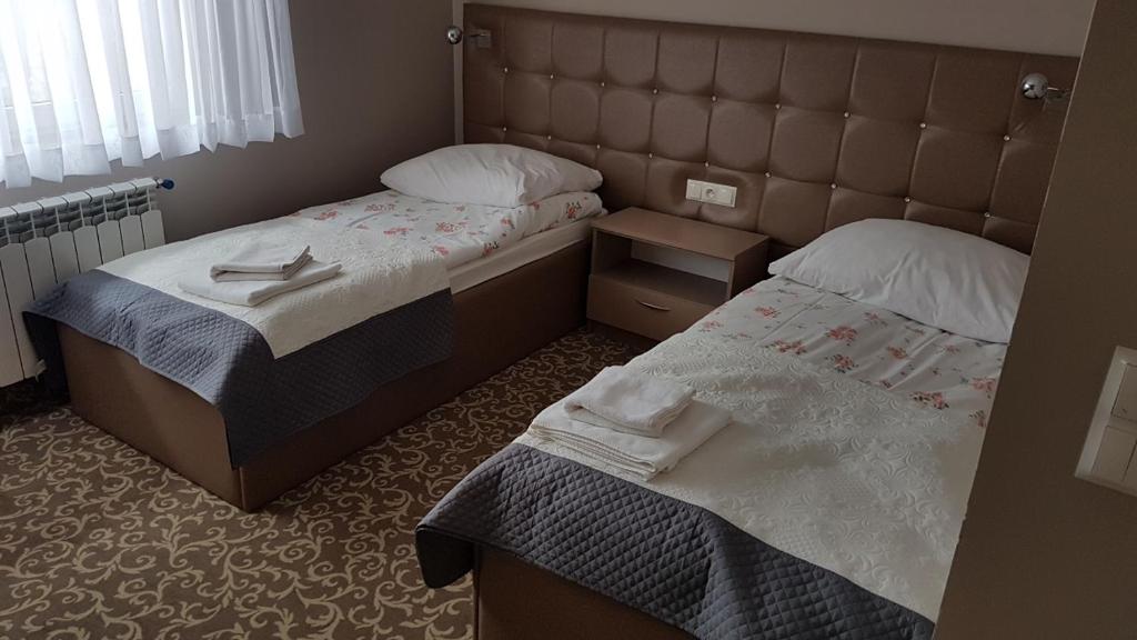Wysokie MazowieckieHotel Gutland的小客房内的两张床和毛巾