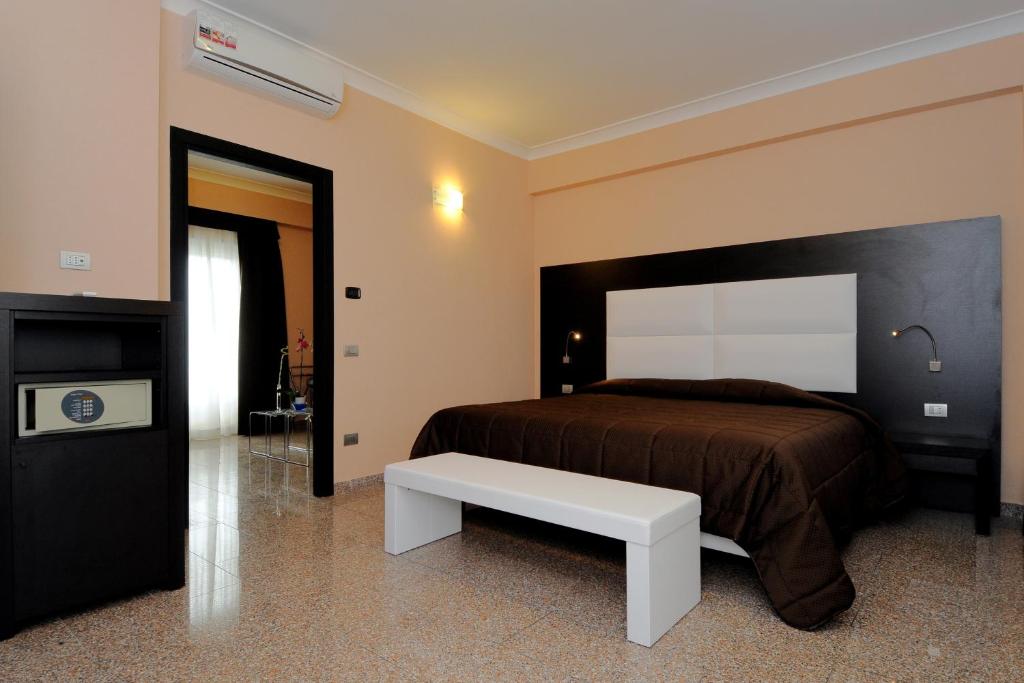 菲乌米奇诺EH Suites Rome Airport Euro House Hotels的一间卧室设有一张大床和一张白色长凳