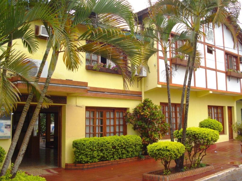 伊瓜苏港罗斯赫勒朝斯旅馆的一座棕榈树的黄色建筑
