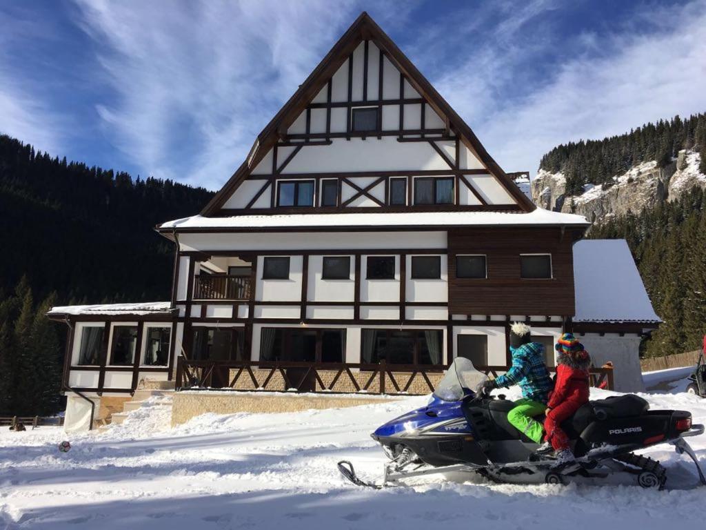 莫罗埃尼Chalet Alpina的两个人在房子前面的雪地车上