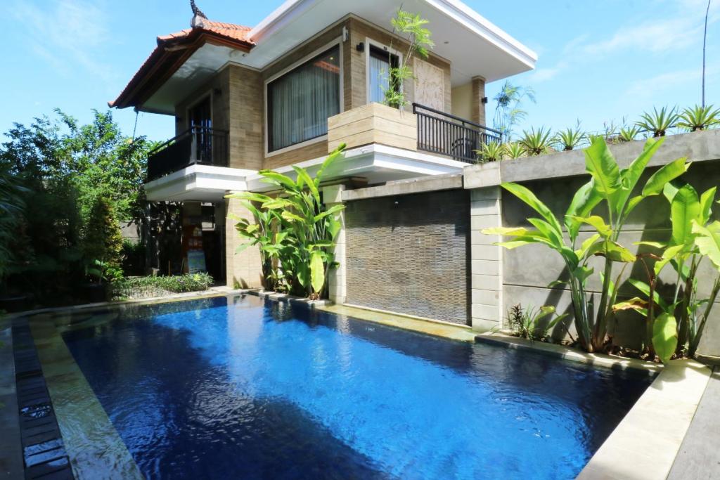 库塔Kondra Premiere Guest House Kuta的房屋前的游泳池