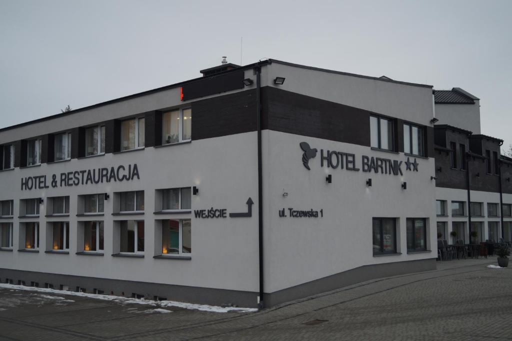 PszczółkiHotel Bartnik的一座白色的大建筑,上面写着鲍曼卡酒店的话