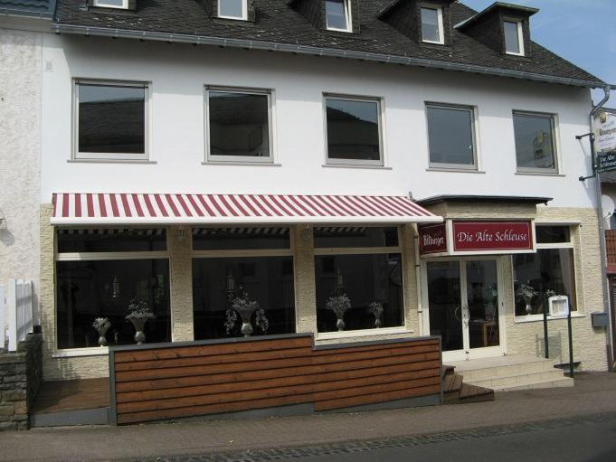 曼德沙伊德Herberg Die alte Schleuse的一座建筑前面的商店,有红色遮阳篷