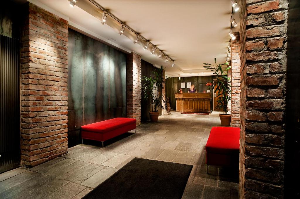 斯德哥尔摩赫尔斯坦酒店的走廊上设有红色座椅和砖墙