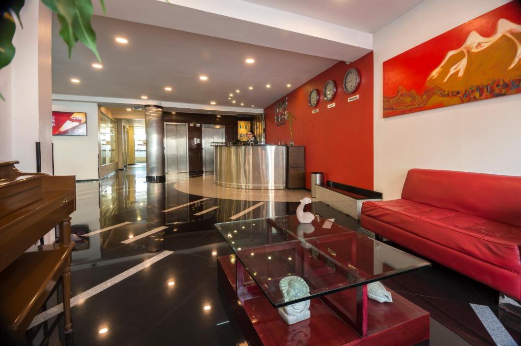 拉巴斯El Rey Palace Hotel的客厅配有红色的沙发和玻璃桌
