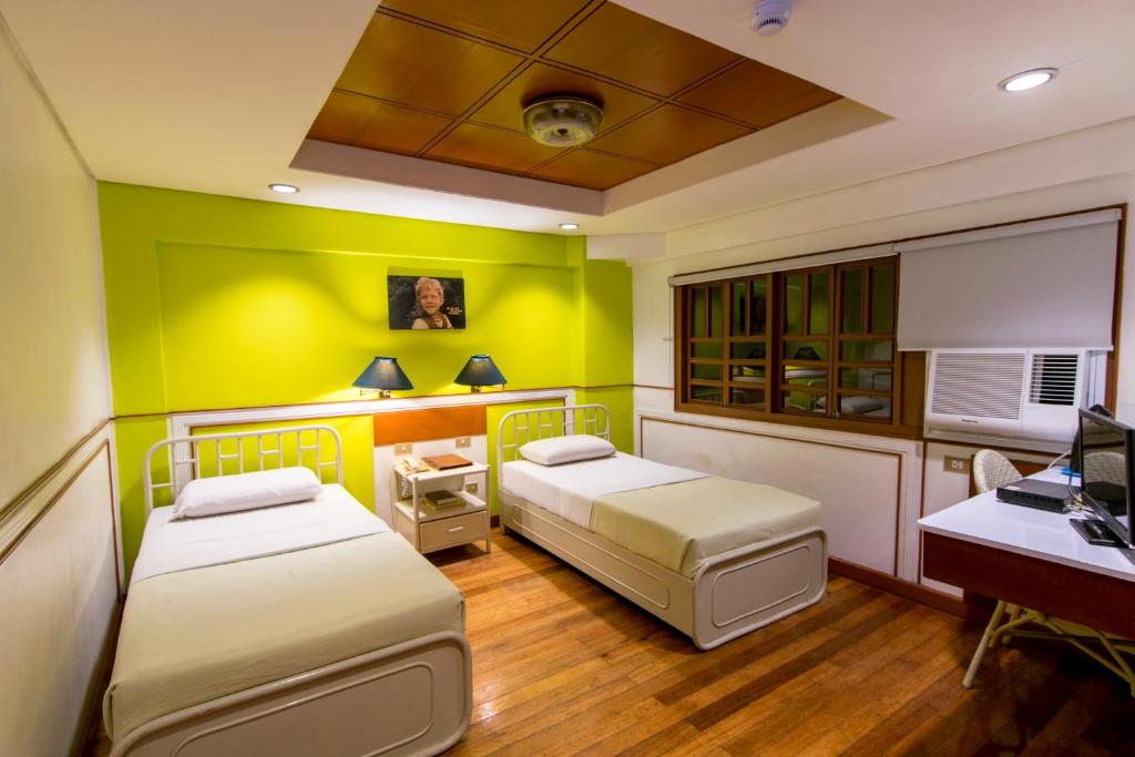达沃市马诺酒店的配有书桌和电脑的客房内的两张床