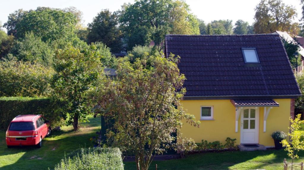 韦森贝格Gästehaus A+C Bovet的停在院子里的黄色房子,有一辆红色的货车