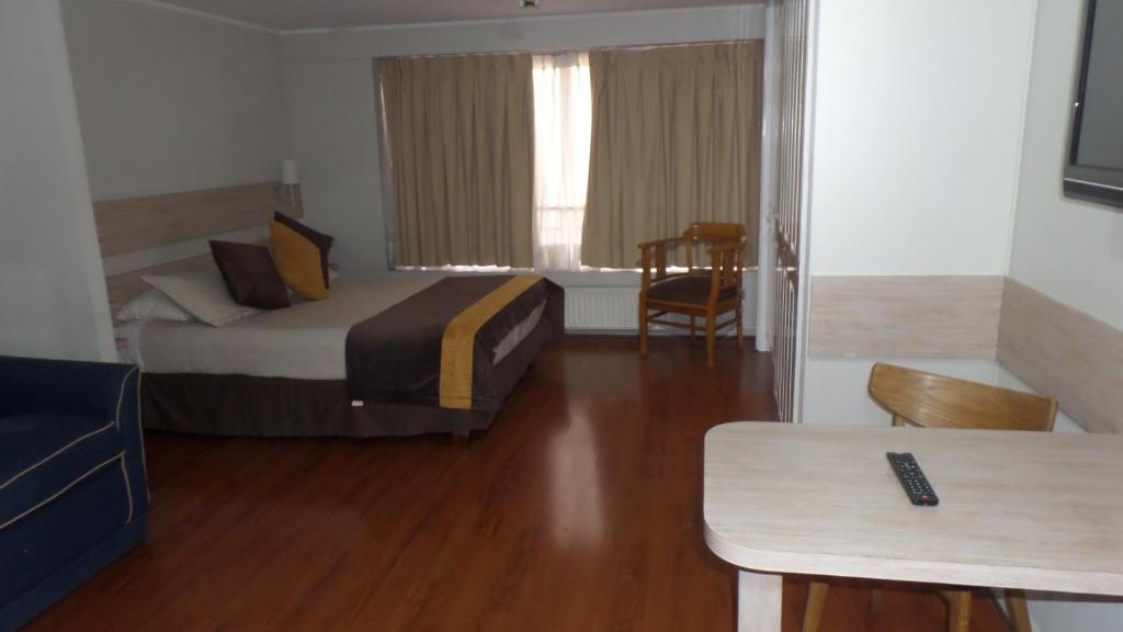 圣地亚哥Luigi's Apart Hotel的酒店客房配有一张床铺和一张桌子。
