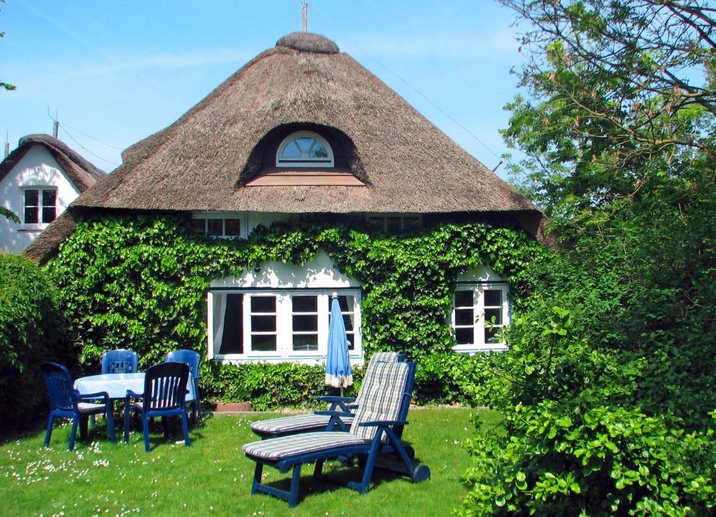 尼布卢姆Föhrer Friesenkate Ost的茅草屋顶房屋,配有椅子和桌子