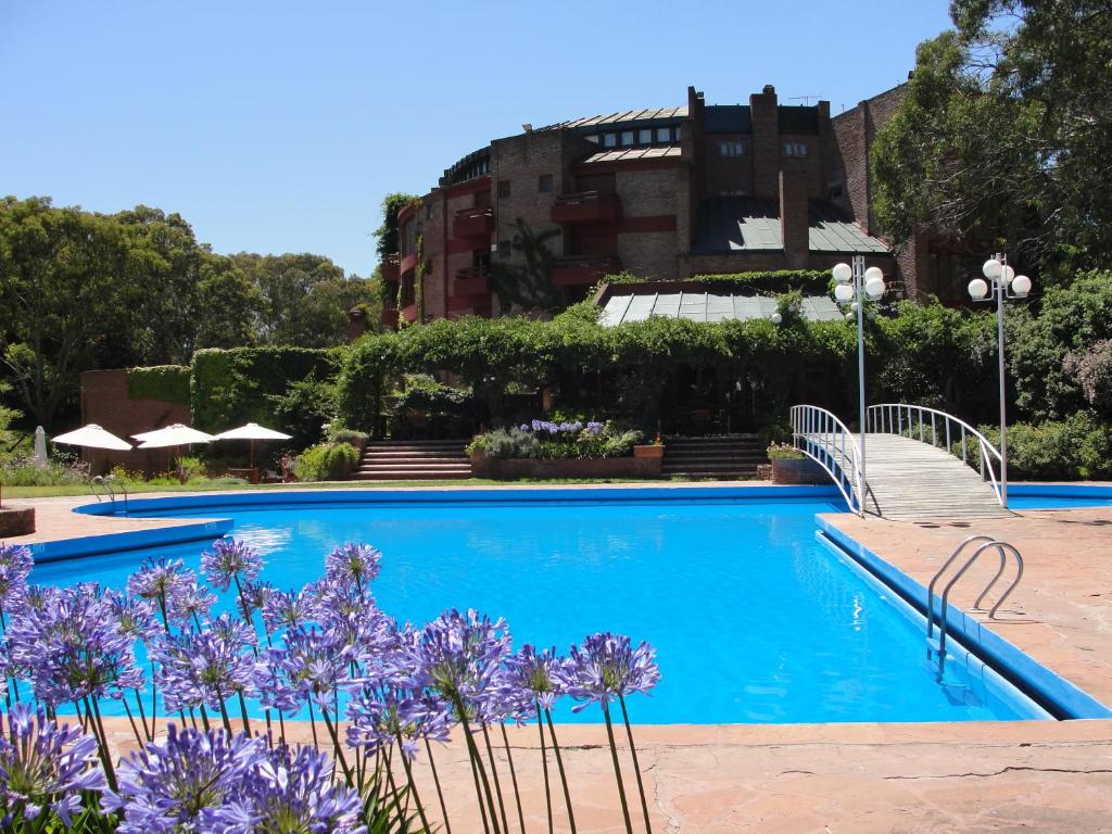 皮纳马尔Hotel del Bosque的一座在建筑前方的紫色花的游泳池