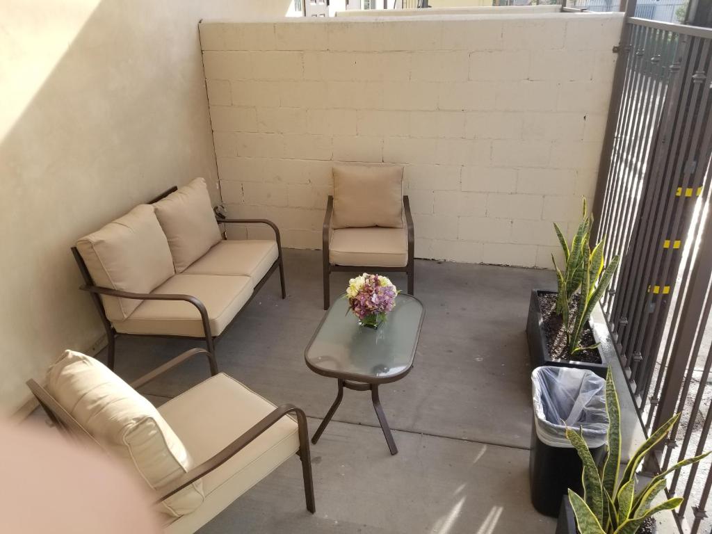 洛杉矶托斯卡纳花园酒店的阳台配有两把椅子、一张沙发和一张桌子