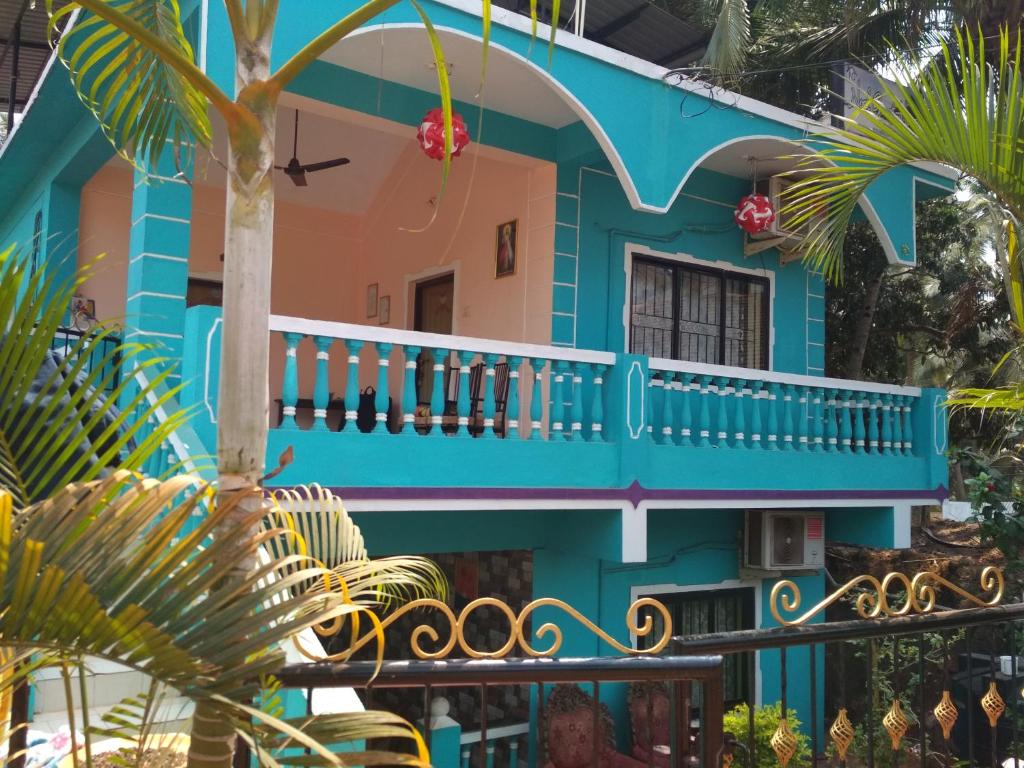 莫尔穆冈Noel Guest House的带阳台和棕榈树的蓝色房屋
