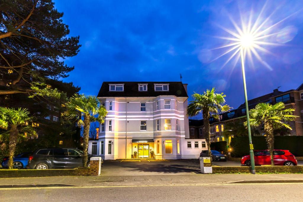 伯恩茅斯康诺特旅馆的一座大型白色房子,拥有棕榈树和街灯
