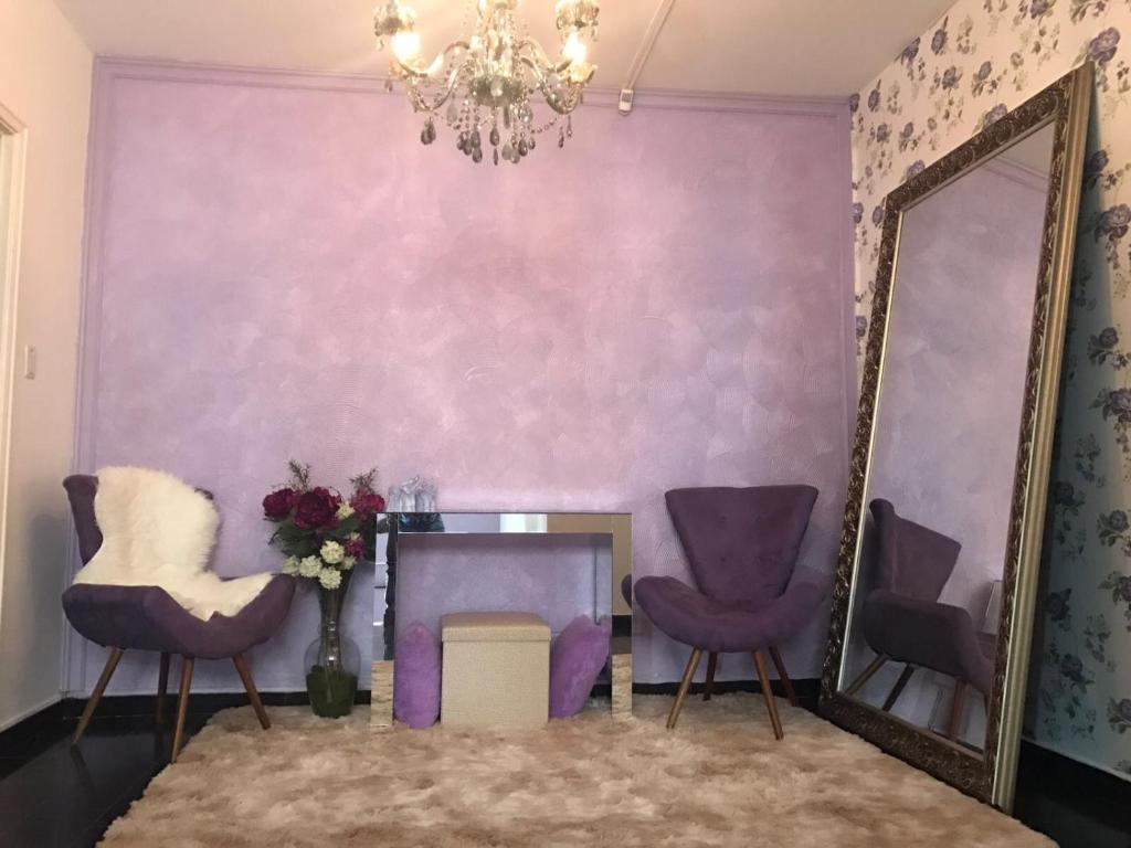 隆德里纳Pousada Hostel Universitário的紫色的客房配有两把椅子和镜子