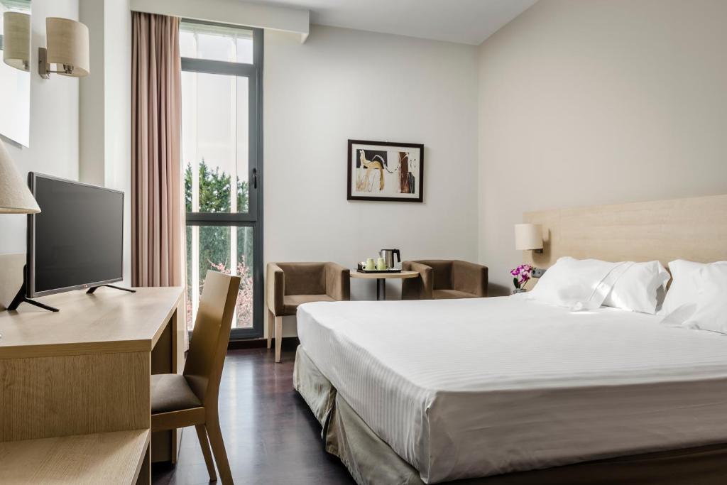 圣胡安德斯皮巴塞罗那盖特埃克酒店的酒店客房配有一张床、一张书桌和一台电视。