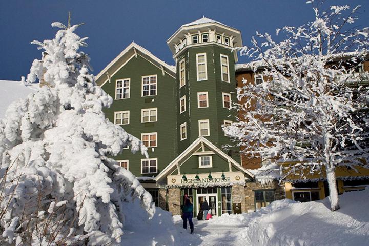 斯诺肖高地旅馆的一座绿色的大建筑,前面有雪覆盖的树木