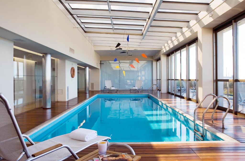 布宜诺斯艾利斯马德罗布宜诺斯艾利斯酒店的大楼内一个带椅子和桌子的游泳池