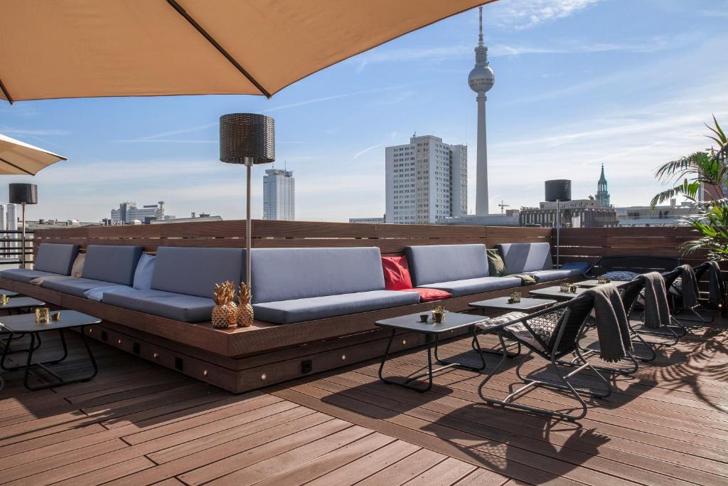 柏林Hotel ZOE by AMANO的屋顶的沙发,配有桌子和雨伞